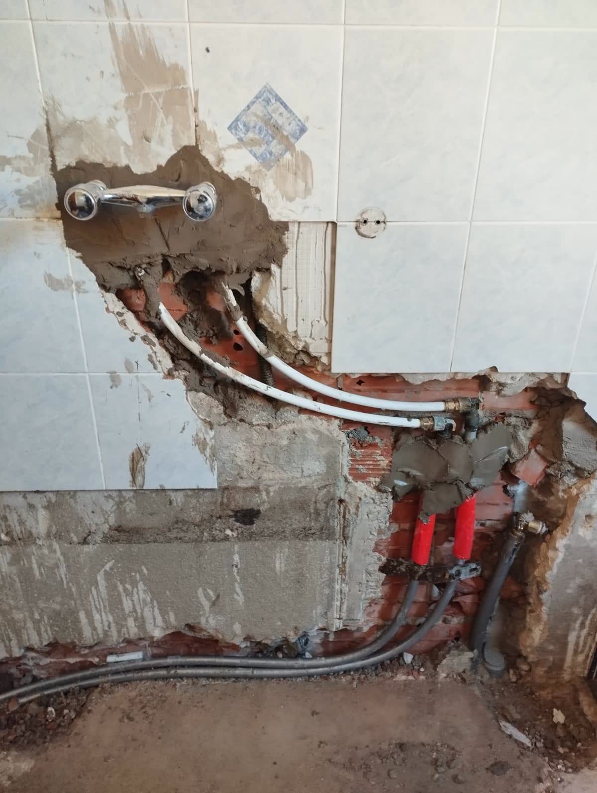 Tracce aperte nel muro del bagno con i tubi multistrato e i collettori nuovi